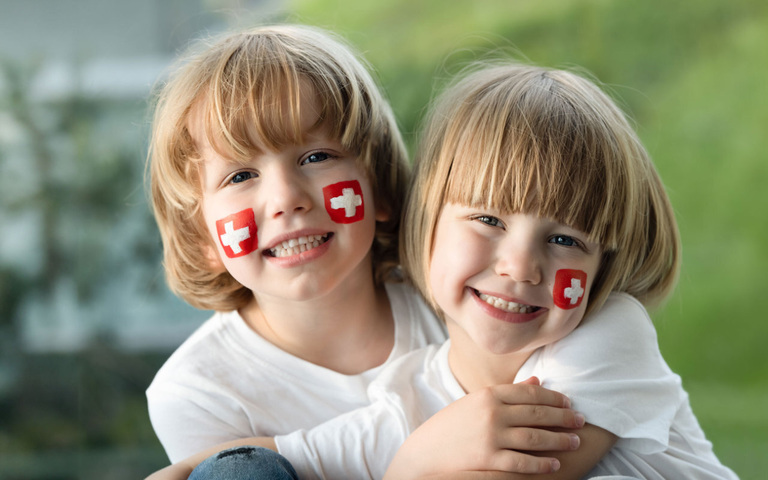 zwei Kinder mit Schweizer Flagge auf der Wange