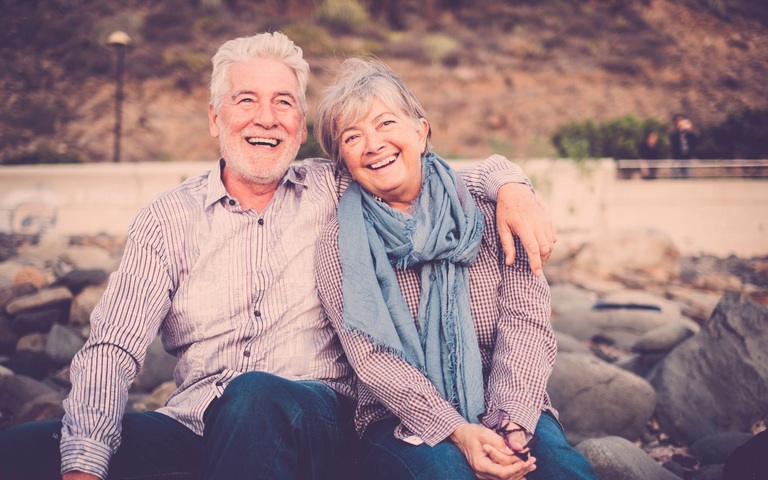 ein älteres Paar hält sich lachend im Arm 