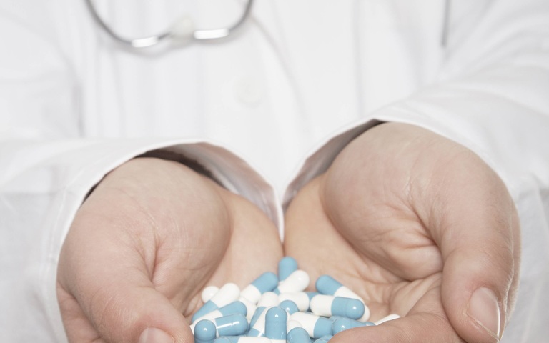 Arzt mit einer Hand voll Tabletten
