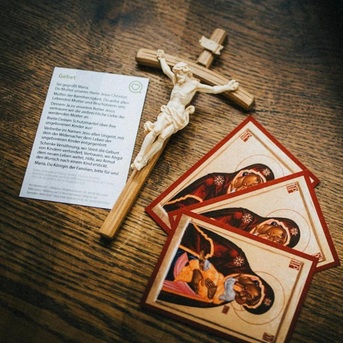 ein Holzkreuz mit Gebetskärtchen zur Mutter unseres Herrn