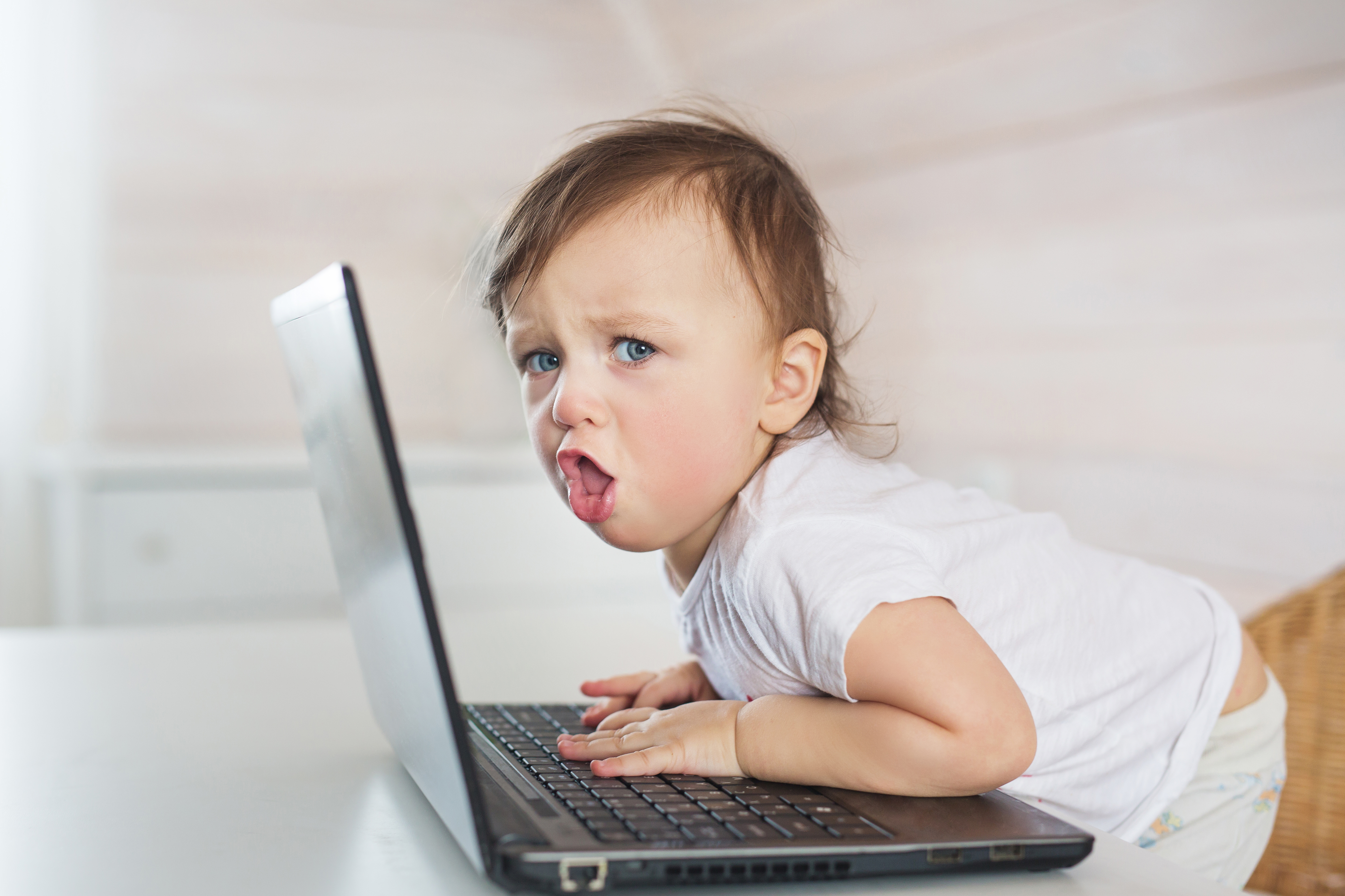 Wütendes kleines Baby-Mädchen mit einem Laptop