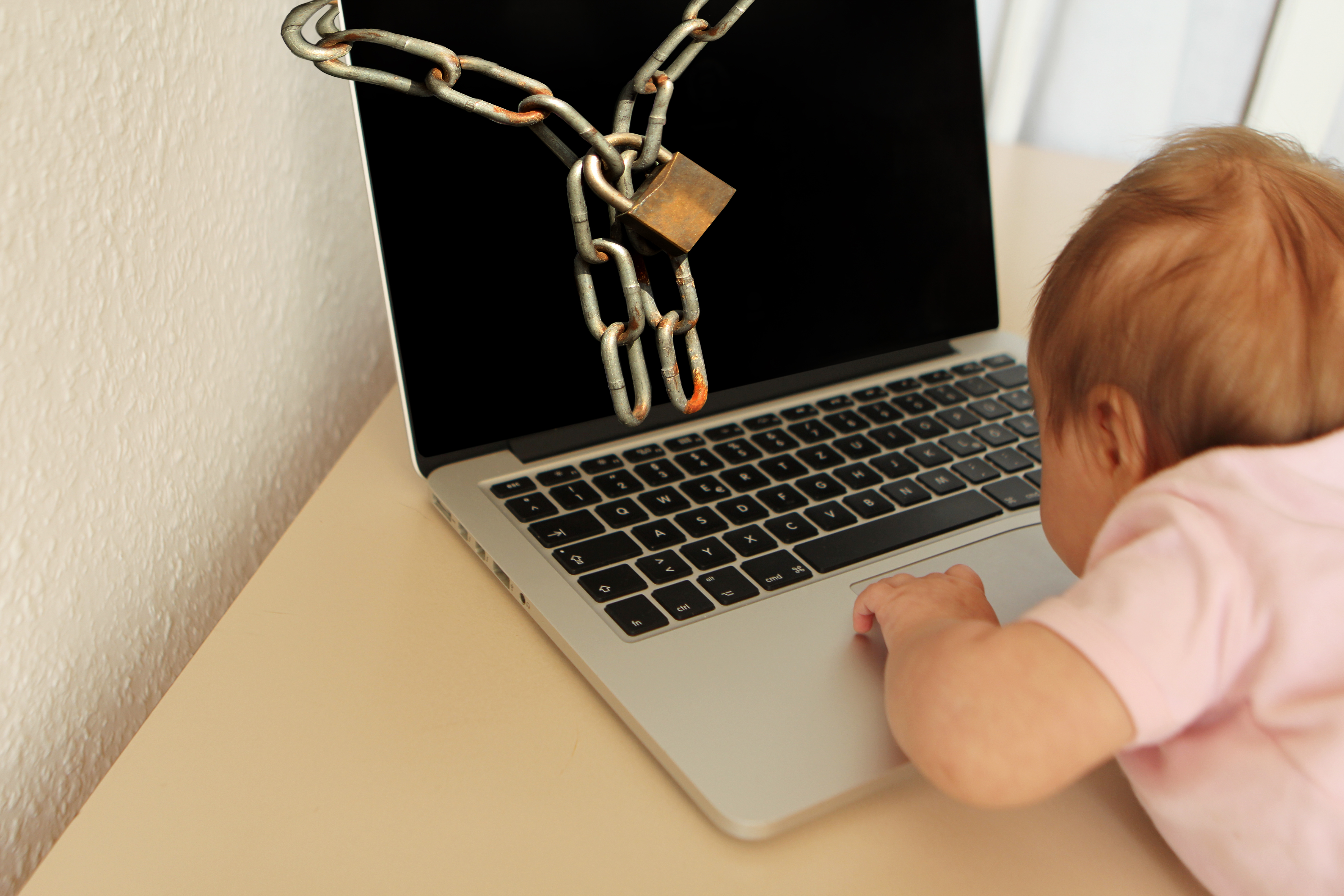 Baby am Laptop mit Kette verschlossen