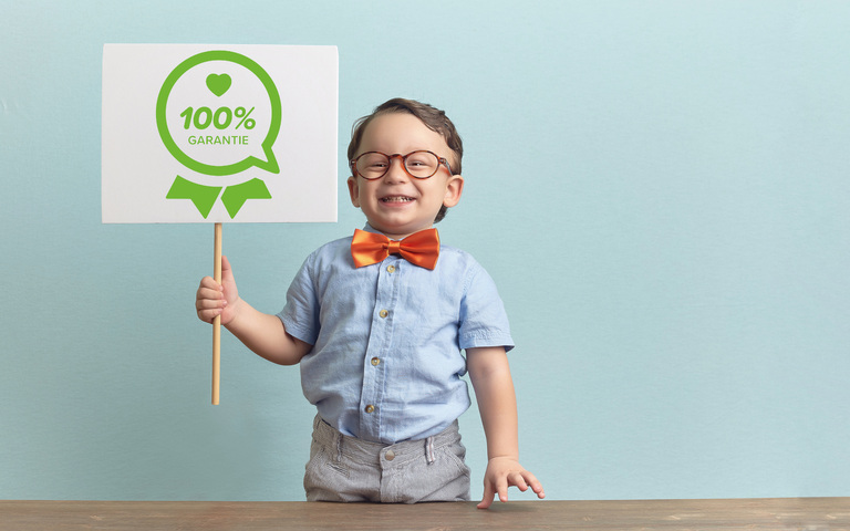 kleiner Junge hält stolz 100% Garantie-Schild hoch