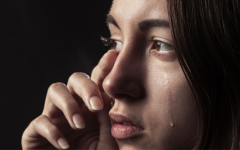 eine verzweifelte junge Frau wischt sich die Tränen weg