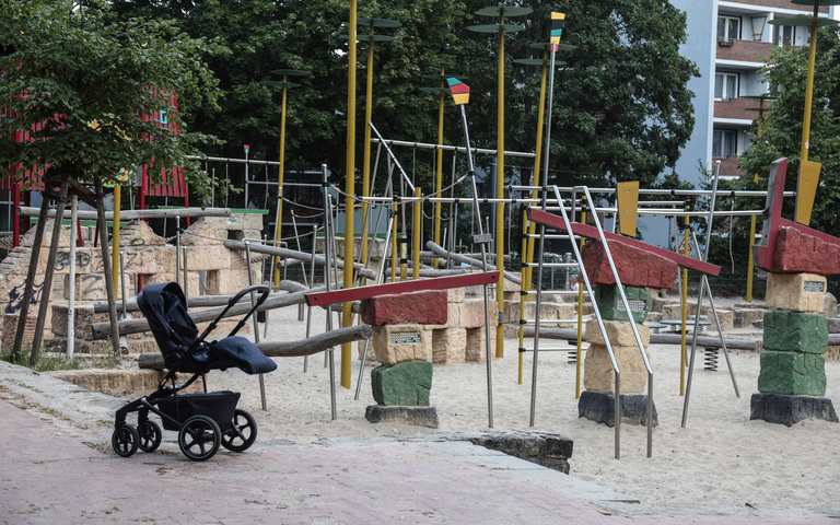 Ein leerer Kinderwagen auf einem Spielplatz.