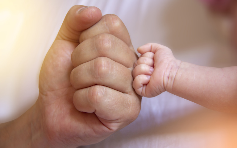 Hand Erwachensener und Baby