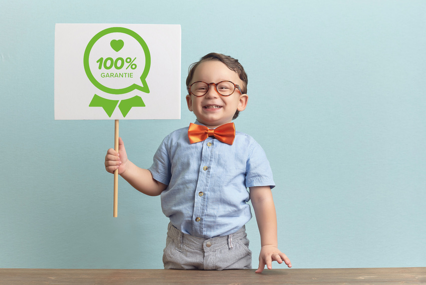 kleiner Junge hält stolz 100% Garantie-Schild hoch