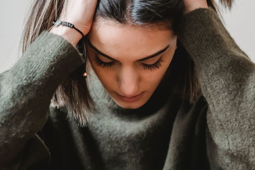 eine junge Frau rauft sich vor Verzweiflung die Haare